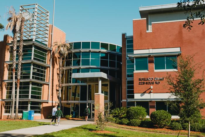 A student standing in front of the Davis College of Business & Technology.